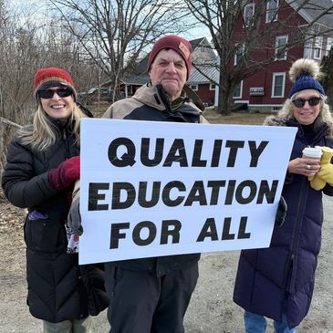Three people outdoors holding a sign that says "QUALITY EDUCATION FOR ALL."