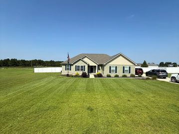 A single-story house with a large green lawn under a clear blue sky.