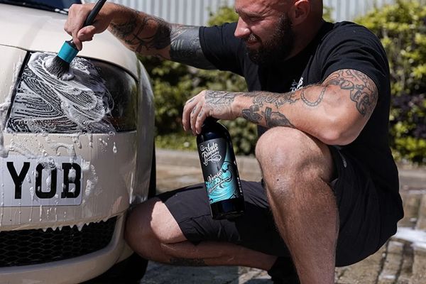 A guy cleaning with detailing brush to prepare Audi headlight for a Headlight Restoration Service.