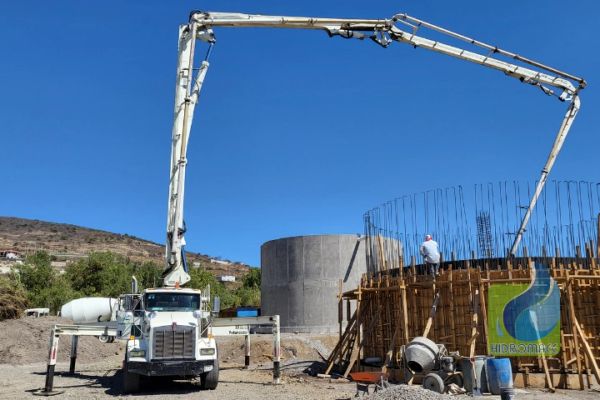 Construcción con camión de concreto y grúa articulada.
