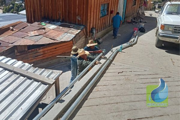 Trabajadores instalan tuberías en una calle empinada.