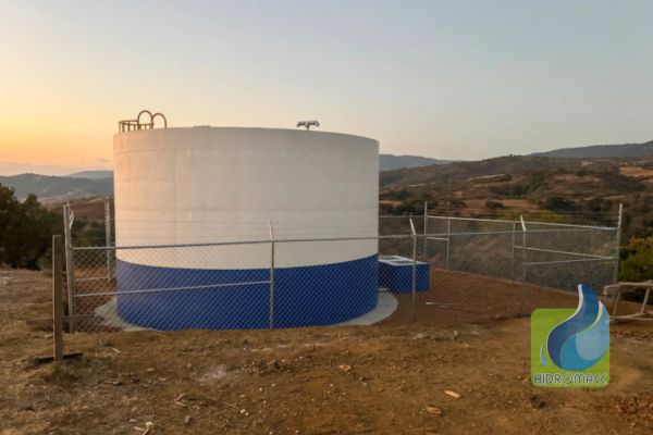 Tanque de agua grande en terreno abierto con cerca perimetral.