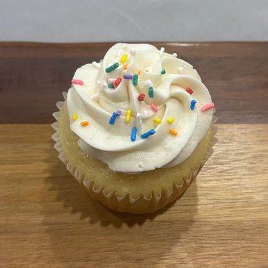 Vanilla cupcake with vanilla frosting and rainbow sprinkles 