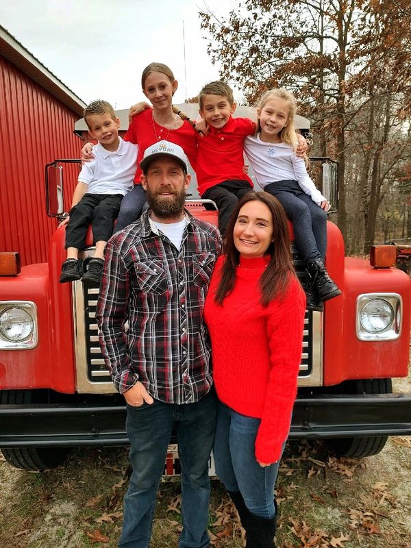 Family of six in front of a red truck outdoors.
