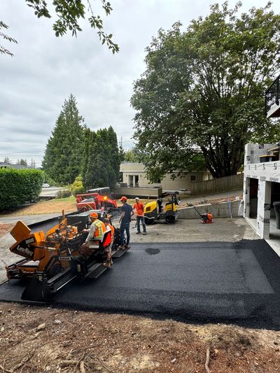 Worker using asphalt machinery to resurface an asphalt driveway.
