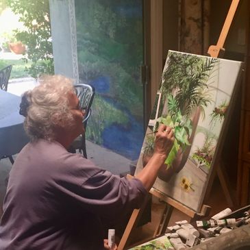 The artist working at home with the natural light from a skylight above and patio doors open to a ca