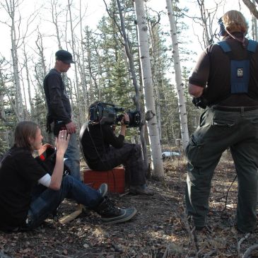 Film crew shooting in a wooded area during daytime.