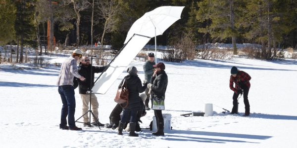A group of people setting up photography equipment in a snowy outdoor area.