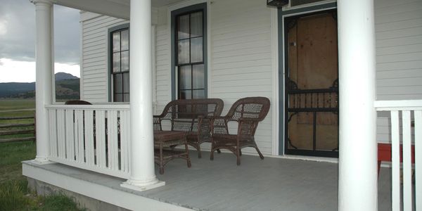 A quiet porch with wicker chairs and a view of fields and mountains.