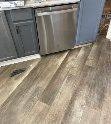 New wood-look flooring installed in a kitchen with stainless steel dishwasher.