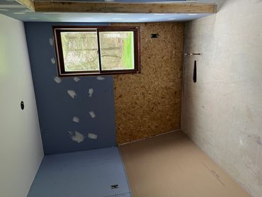Room under renovation with patchy blue walls and unfinished floor.