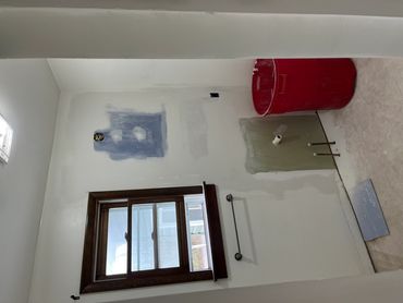Bathroom under renovation with exposed plumbing and a red trash bin.