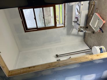 An unfinished room with painting tools and a window letting in natural light.