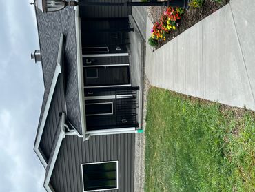 Modern gray house with a concrete pathway and flower bed.