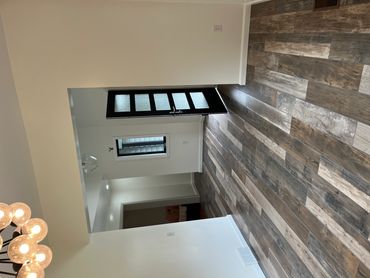 Modern room with wood-patterned flooring and a black door with frosted glass panels.
