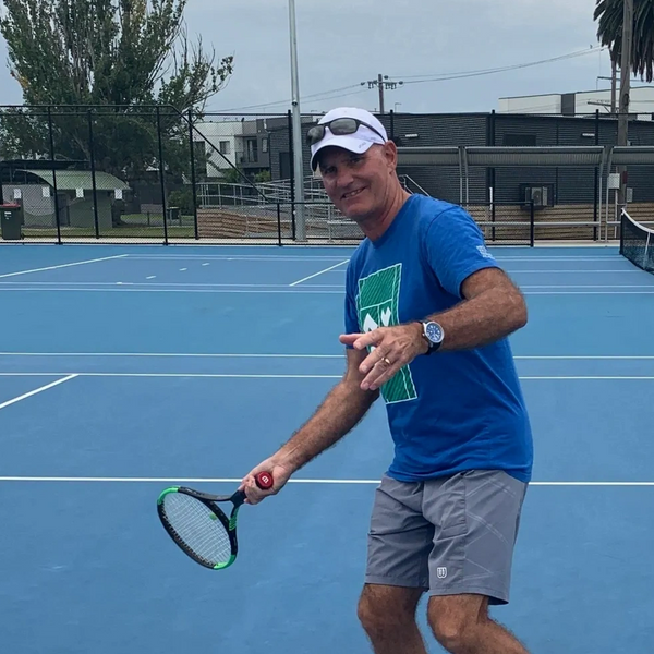 Man in blue shirt playing pickleball on outdoor court.