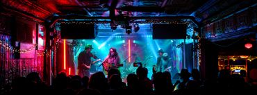 Live band performing on a colorful stage with an audience.