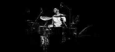 Drummer playing passionately in a black and white setting.