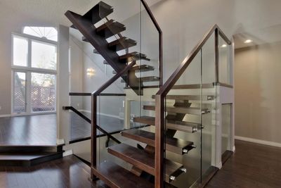 Modern staircase with dark wood steps and glass railings in a bright home interior.