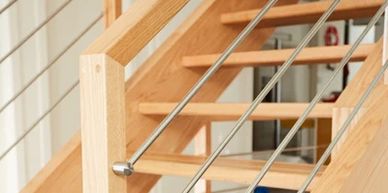 Modern wooden staircase with metal railing cables.