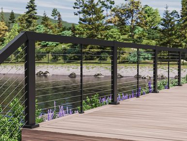 Modern cable railing on a wooden deck overlooking a river and trees.