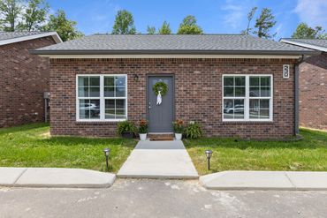 Single-story brick house with a central gray door and two large windows.
