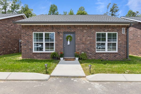 Single-story brick house with a central gray door and two large windows.