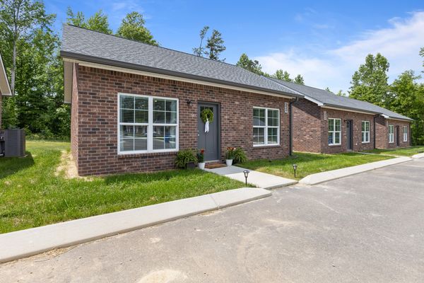 Row of modern brick townhouses with well-maintained lawns and clear skies.