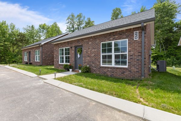 Single-story brick houses with well-kept lawns on a sunny day.