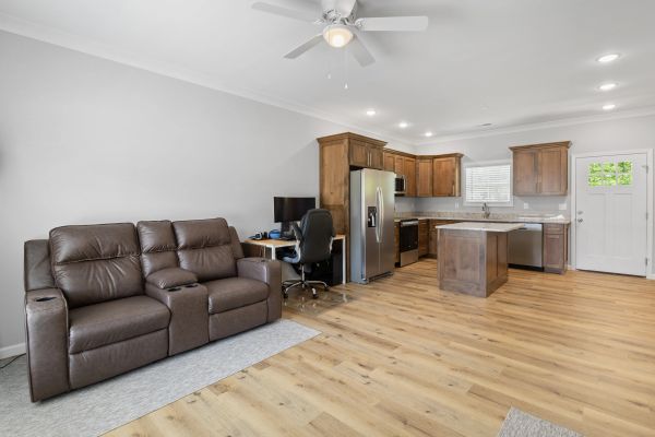 Modern open-plan kitchen and living area with wooden cabinets and leather sofa.