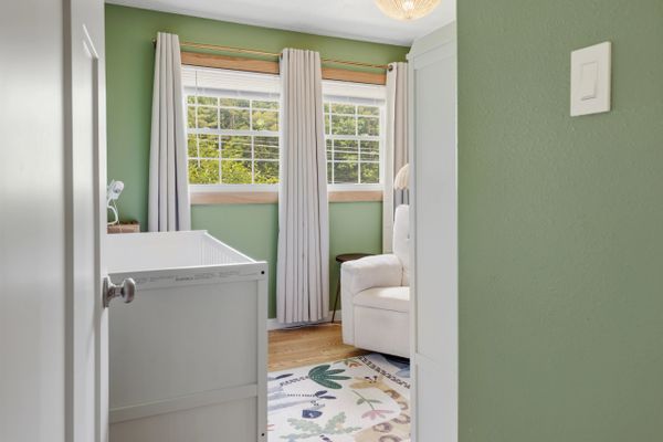 Cozy nursery with green walls, white crib, and nature-themed rug.