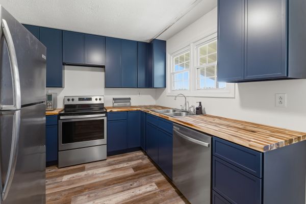 Modern kitchen with blue cabinets and wooden countertops.