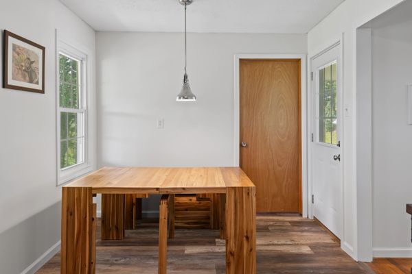 Minimalist dining area with wooden table and pendant light.