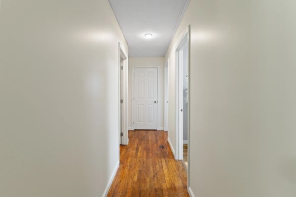 Bright hallway with wooden floor and white doors.