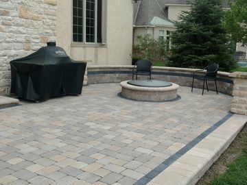 Custom paver patio and outdoor kitchen living space with integrated fire pit.