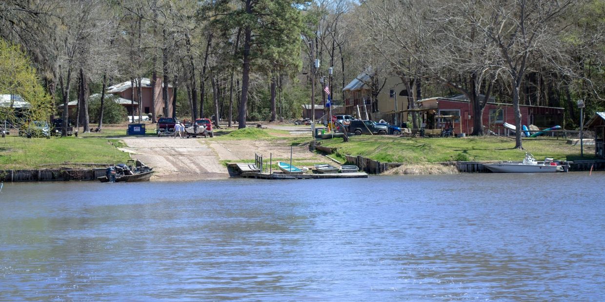 A calm lakeside scene with docks, boats, and houses among trees.