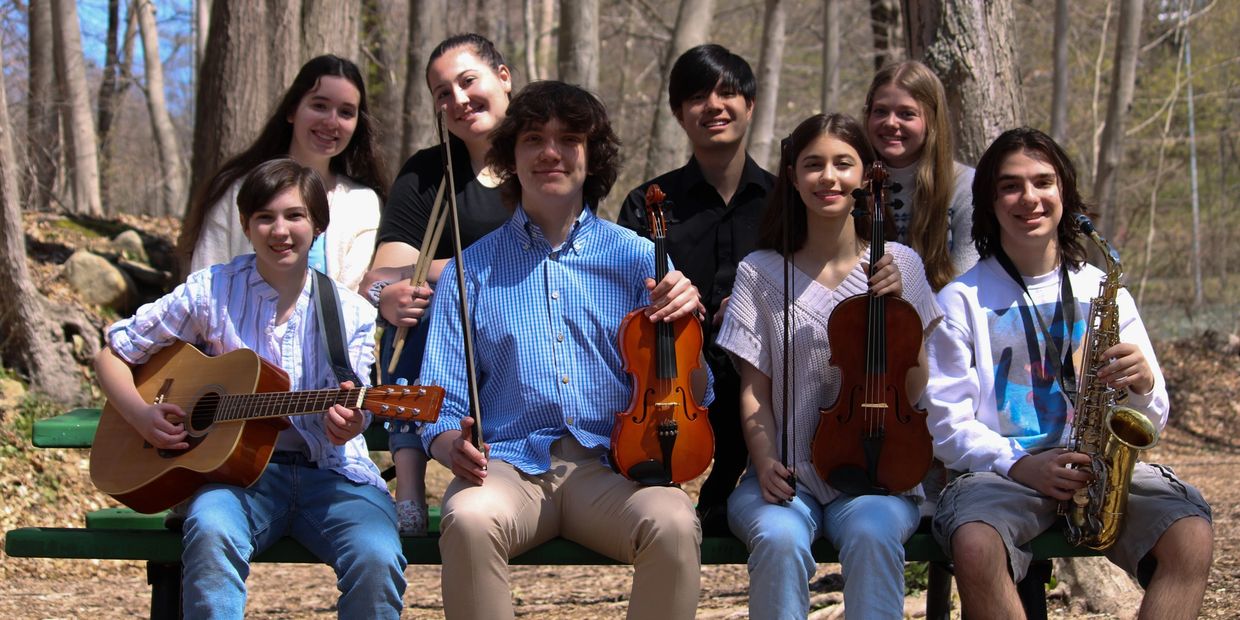 A group posing with musical instruments in the woods