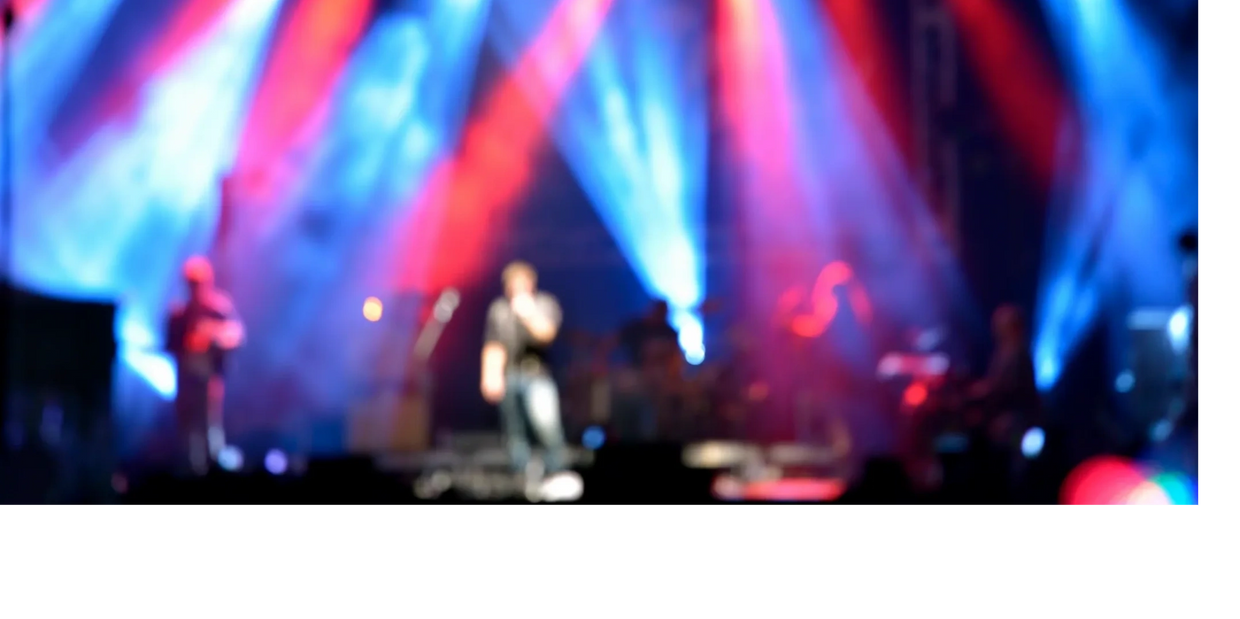Blurry image of a live music concert with vibrant red and blue stage lights.