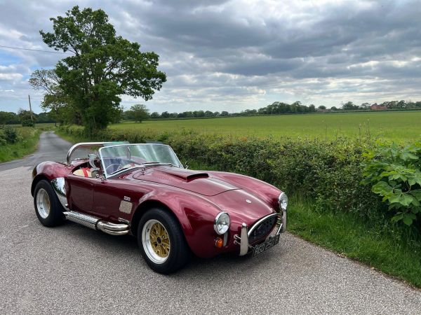Classic red convertible car parked on a country road.
