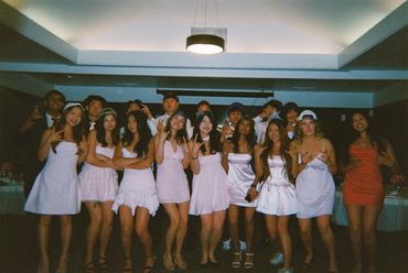 Group of young people posing together at a party in stylish dresses and casual wear.