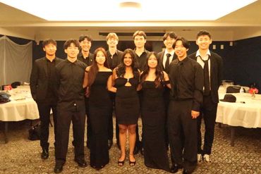 A group of young adults dressed formally, posing indoors.