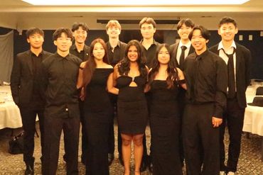 A group of young adults dressed formally, posing indoors.