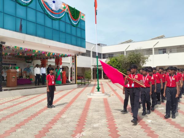 Students in red uniforms participate in a flag ceremony at school.
