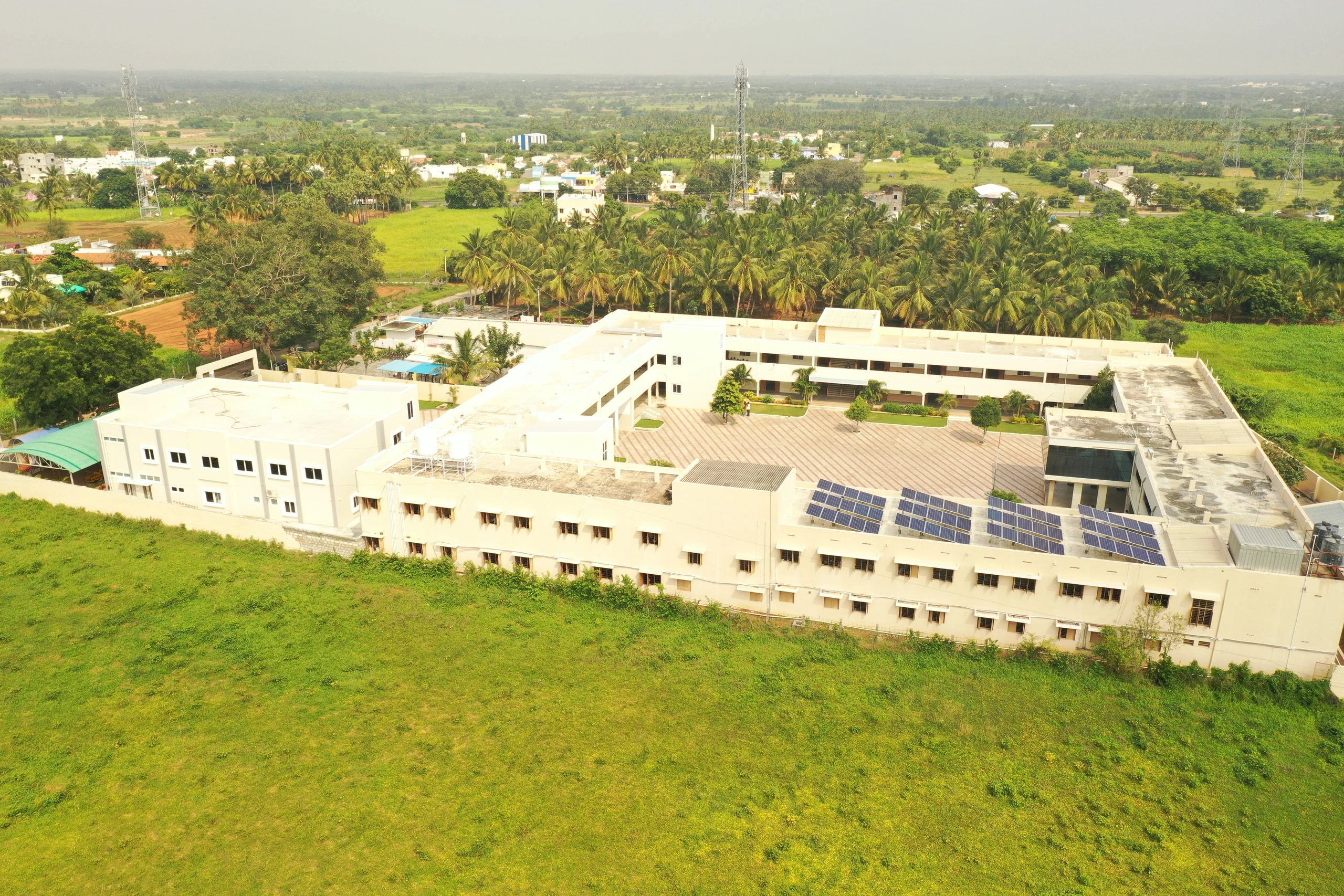 Large building surrounded by greenery and palm trees.