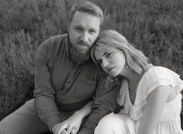 Black and white portrait of a couple seated closely outdoors.
