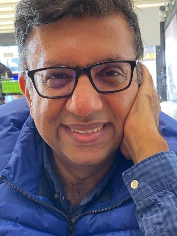 Man wearing glasses and a blue jacket smiling.