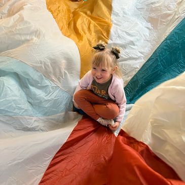 Preschool student playing in the parachute