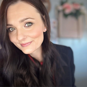 Close-up portrait of a smiling woman with long dark hair and green eyes.