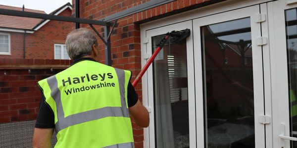 A worker from Harleys Windowshine cleaning a glass door.
