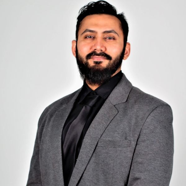 Psychotherapist - Zakir Savai - Headshot - Standing against light grey background with slight smile
